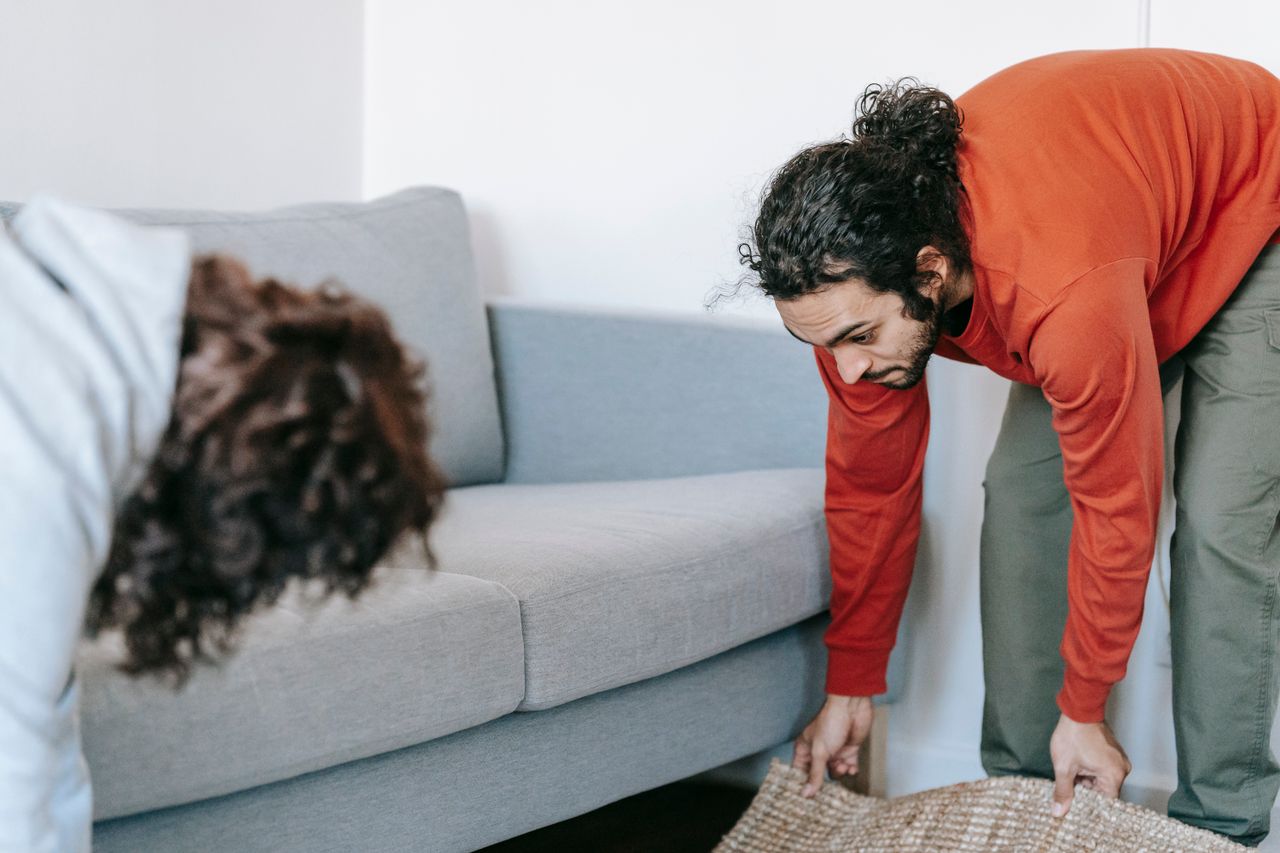 why-choose-us A couple tidying up their living room, organizing furniture and rugs with teamwork.